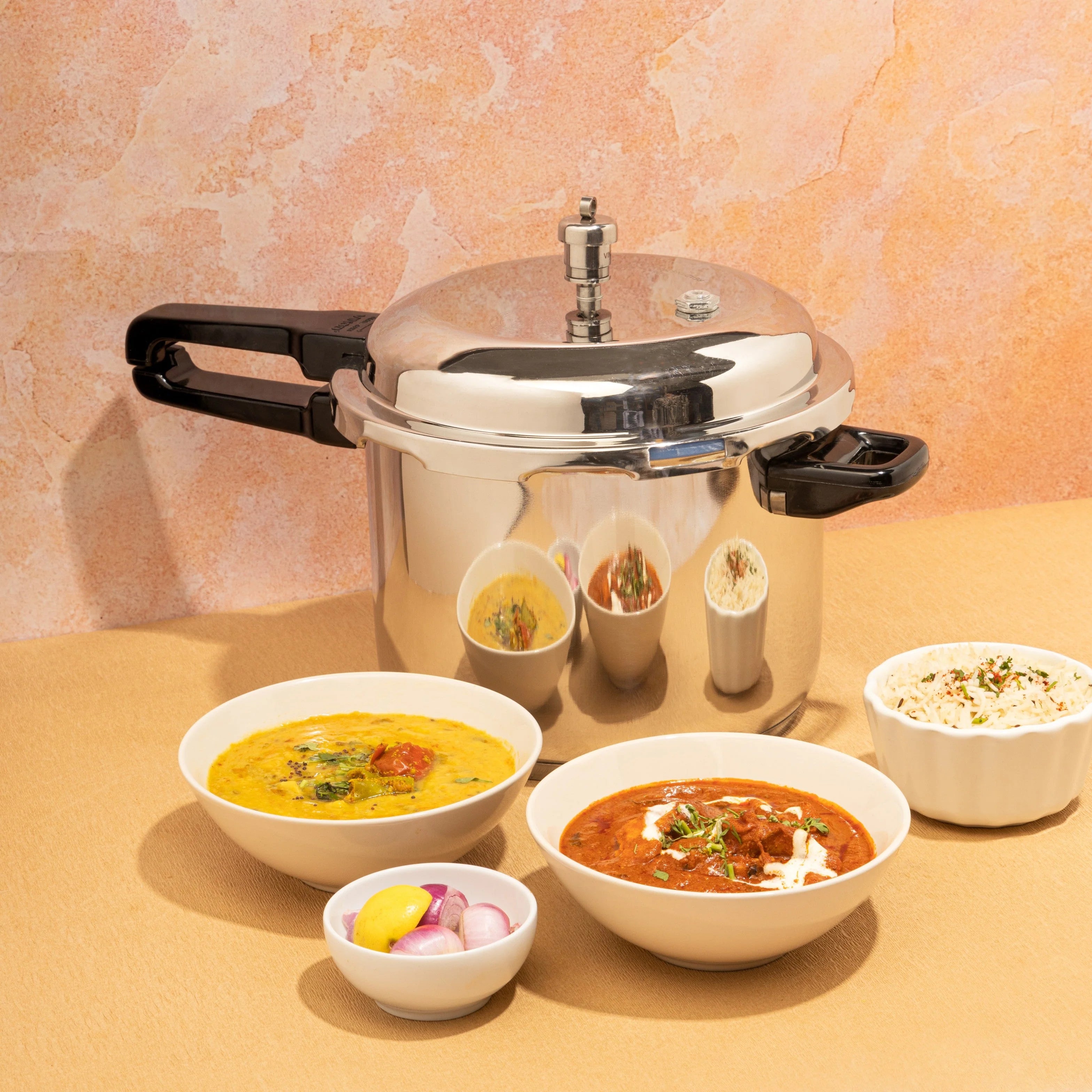 Pressure cooker with various dishes on a beige surface