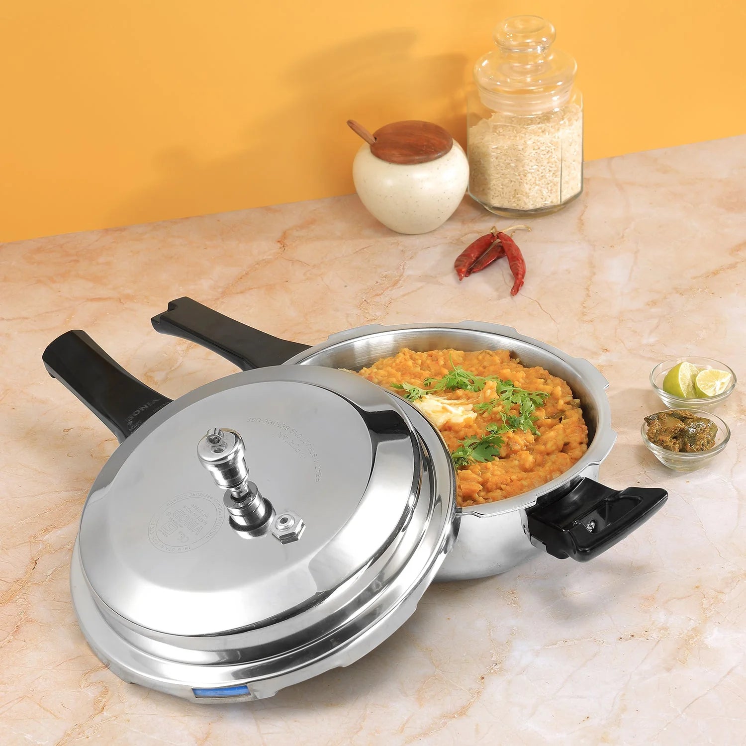 Stainless steel pressure cooker with food on a marble countertop