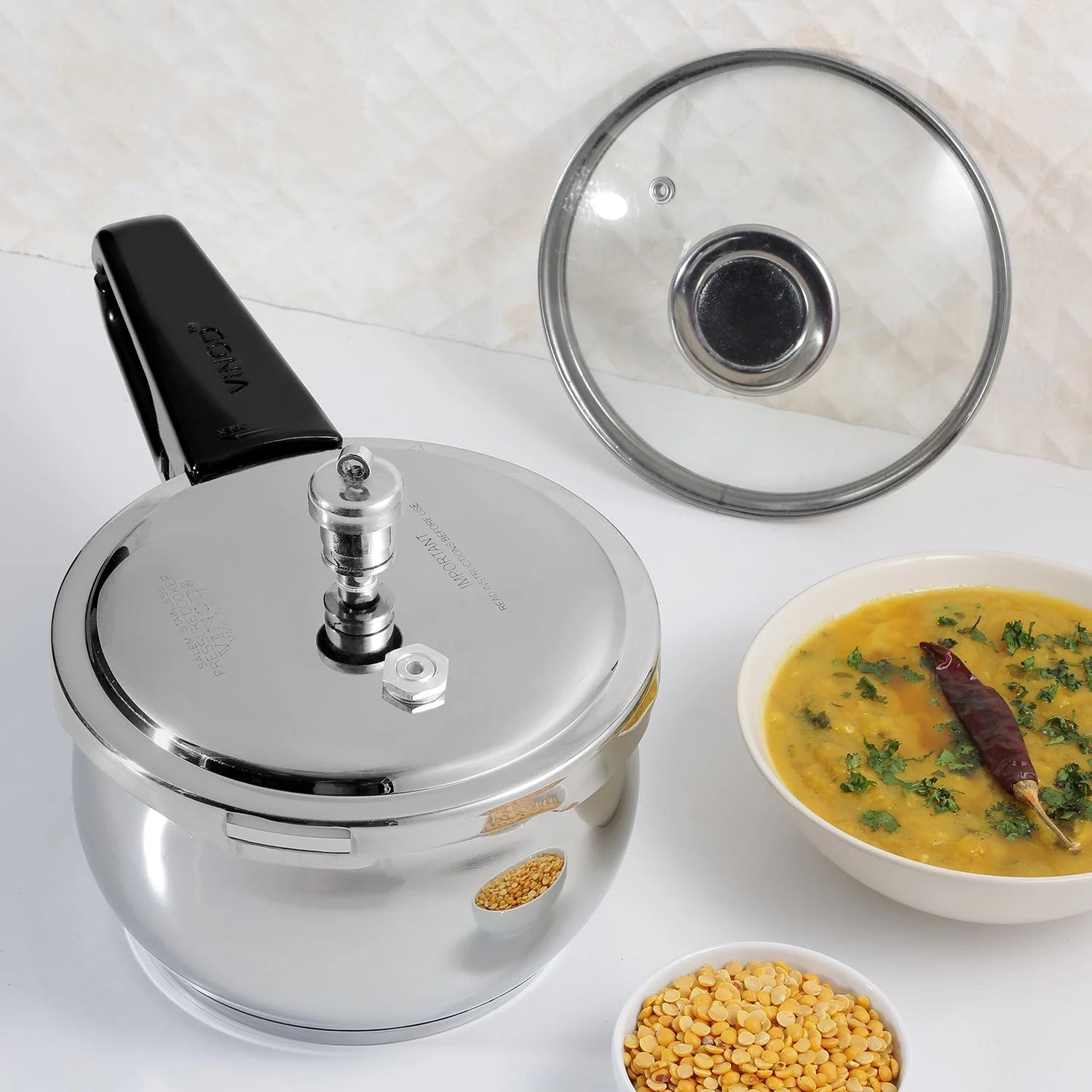 3.5 liter Stainless steel pressure cooker with a bowl of curry and a bowl of lentils on a white background
