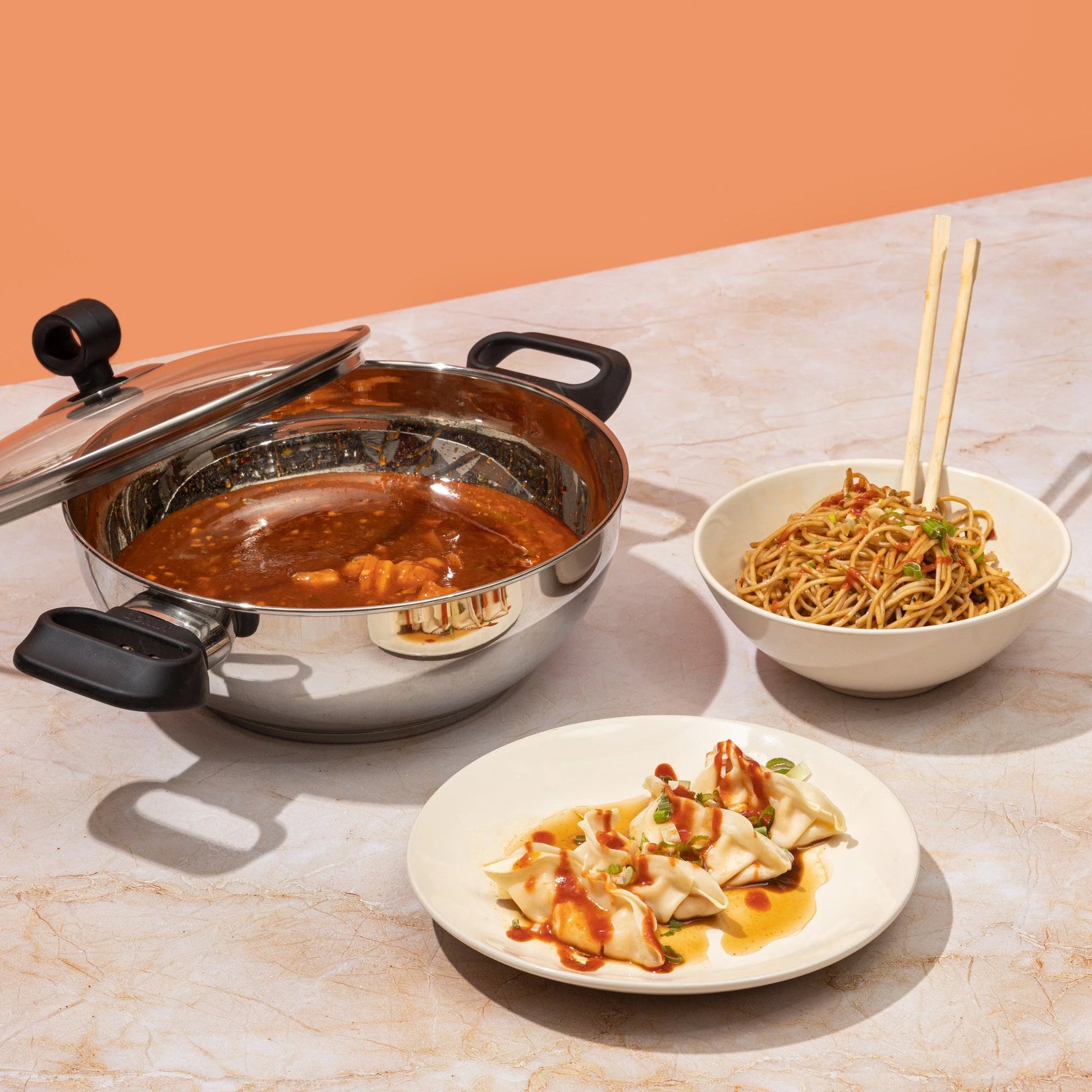 Vinod Deluxe stainless steel kadai used for cooking Asian cuisine, featuring dumplings and noodles, showcasing its versatility