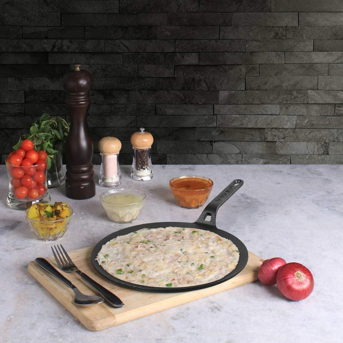 Vinod Legacy Cast Iron Flat Multi Tawa with vegetable pancake cooking on a countertop with condiments